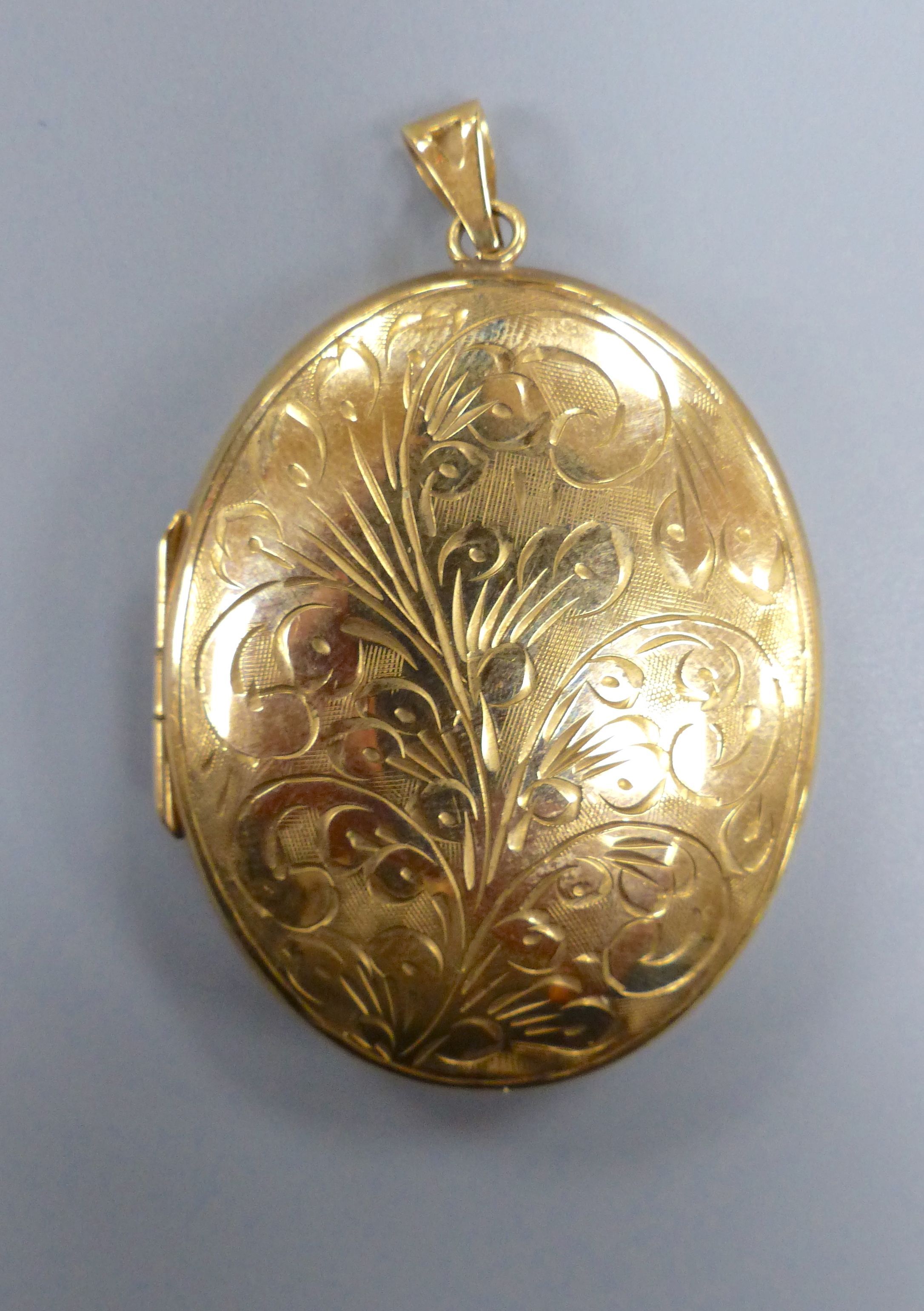 A modern engraved 9ct gold oval locket, 47mm,